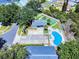 Aerial view of a community pool, shuffleboard court, parking, and clubhouse in a fenced area with palm trees at 1307 Wayne Ave, New Smyrna Beach, FL 32168