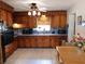 Eat-in kitchen featuring knotty wood cabinets, black appliances, and tiled floor at 1627 Umbrella Tree Dr, Edgewater, FL 32132