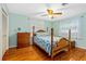 Bright bedroom featuring a ceiling fan, wood floors, and a bed with seashell themed bedding at 1786 Taylor Rd, Port Orange, FL 32128