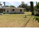 Exterior view of the rear of the home featuring a lush lawn and trees at 1830 Needle Palm Dr, Edgewater, FL 32132