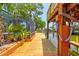 Waterfront dock with a boat lift, stairs to an upper deck, lush greenery, and a screened pool area at 184 Azalea Rd, Edgewater, FL 32141
