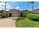 Home with well-kept lawn, driveway, tropical landscaping, and inviting entrance, showcasing curb appeal at 1903 Sprucewood Way, Port Orange, FL 32128