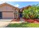 Home with a driveway, tropical landscaping, and an inviting front entrance, showcasing curb appeal at 1903 Sprucewood Way, Port Orange, FL 32128