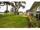 Spacious green backyard with a patio area, bordered by shrubbery, and serene pond views at 1903 Turnbull Lakes Dr # 1903, New Smyrna Beach, FL 32168