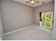 A bedroom with gray carpet has access to a balcony with a sliding glass door, and a ceiling fan at 1903 Turnbull Lakes Dr # 1903, New Smyrna Beach, FL 32168