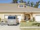 Charming beige home featuring an arched entryway, manicured lawn, and attached two-car garage on a sunny day at 1903 Turnbull Lakes Dr # 1903, New Smyrna Beach, FL 32168