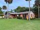 Attractive brick home with mature landscaping, lush lawn, and accent lighting creates an inviting curb appeal for evening enjoyment at 208 Wellington Dr, Daytona Beach, FL 32119