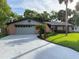 Charming brick home featuring a well-manicured lawn, mature landscaping, a spacious driveway and an attached garage at 208 Wellington Dr, Daytona Beach, FL 32119