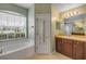 Bright bathroom features a soaking tub under a window and a vanity with a large mirror and wooden cabinets at 2435 Alton Rd, Deltona, FL 32738