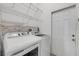 Modern laundry room features a washer and dryer with white cabinets and stone backsplash at 2435 Alton Rd, Deltona, FL 32738