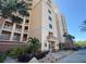 Condo building featuring multiple balconies and an inviting entrance surrounded by palm trees, benches, and tropical plants at 250 Minorca Beach Way # 206, New Smyrna Beach, FL 32169