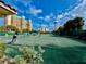 Tennis courts with well-maintained green surface, surrounded by palm trees and residential buildings, under a blue sky at 250 Minorca Beach Way # 206, New Smyrna Beach, FL 32169