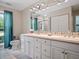 Well-lit bathroom with double sinks, a large mirror, and tiled floors at 257 Sweet Bay Dr, New Smyrna Beach, FL 32168
