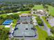 Aerial view features multiple tennis courts, clubhouse, pool, landscaping, parking, and a partial golf course view at 257 Sweet Bay Dr, New Smyrna Beach, FL 32168