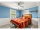 Cozy bedroom featuring blue walls, white wainscoting, and a colorful striped bedspread at 2576 Sunset Dr, New Smyrna Beach, FL 32168