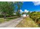 Charming home featuring a long driveway, tropical landscaping, a vibrant red door and attached garage at 2576 Sunset Dr, New Smyrna Beach, FL 32168
