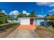Charming single-story home with a white garage door, bright red door, and colorful landscaping at 2576 Sunset Dr, New Smyrna Beach, FL 32168