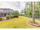 Expansive backyard with lush landscaping, privacy fence, and screened-in pool at 260 Portofino Blvd, New Smyrna Beach, FL 32168