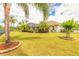 Expansive backyard featuring lush landscaping, mature palms, and a screened-in pool area at 260 Portofino Blvd, New Smyrna Beach, FL 32168