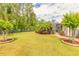 Beautifully landscaped backyard with a well-maintained lawn, ornamental trees, and a decorative fence at 260 Portofino Blvd, New Smyrna Beach, FL 32168