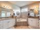 A luxurious bathroom featuring a soaking tub, double vanities with granite countertops, and tiled flooring at 260 Portofino Blvd, New Smyrna Beach, FL 32168
