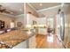 Open-concept kitchen with stainless steel appliances, granite countertops, white cabinets, and hardwood flooring at 260 Portofino Blvd, New Smyrna Beach, FL 32168