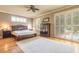 Bright main bedroom featuring hardwood floors, ceiling fan, and French door access to the outdoor pool area at 260 Portofino Blvd, New Smyrna Beach, FL 32168