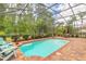 Backyard pool area with screened enclosure, patio furniture, and brick paved deck at 260 Portofino Blvd, New Smyrna Beach, FL 32168