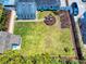 Aerial view of a well-maintained backyard, boasting a fire pit area, green lawn, and perimeter landscaping at 2714 Yule Tree Dr, Edgewater, FL 32141