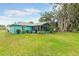 View of the house from the large grassy backyard with screened in back porch and mature trees at 2726 Victory Palm Dr, Edgewater, FL 32141
