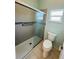 Modern bathroom featuring tiled shower, glass door, grab bar, and toilet next to the window at 3303 Victory Palm Dr, Edgewater, FL 32141