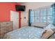 Cozy bedroom with twin beds, an orange accent wall, and natural light from a nearby window at 3509 S Atlantic Ave # 102 And 103, New Smyrna Beach, FL 32169