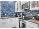 Modern kitchen with white cabinetry, stainless steel appliances, and a blue tiled backsplash at 3509 S Atlantic Ave # 102 And 103, New Smyrna Beach, FL 32169