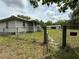 Exterior view of the house and the outbuilding, surrounded by trees and a fence at 3625 Pioneer Trl, New Smyrna Beach, FL 32168