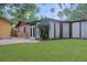 Backyard view featuring a large green lawn, patio, glass enclosed lanai, and partial view of brick home at 3736 Paige St, Port Orange, FL 32129