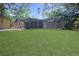 Backyard view featuring a large green lawn, patio, glass enclosed lanai, and brick home at 3736 Paige St, Port Orange, FL 32129