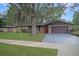 Charming single-story brick home featuring an attached garage, manicured lawn and a bright red front door at 3736 Paige St, Port Orange, FL 32129