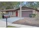 Brick home featuring a red front door, attached garage, and mature landscaping at 3736 Paige St, Port Orange, FL 32129