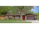 Charming one-story brick home with a red front door, mature trees, and well-maintained lawn at 3736 Paige St, Port Orange, FL 32129