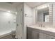 Bright bathroom featuring a walk-in shower, gray vanity with marble countertop and framed mirror at 3808 Saxon Dr, New Smyrna Beach, FL 32169