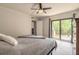 Bright bedroom featuring a ceiling fan, balcony access, and a dark wood dresser at 3808 Saxon Dr, New Smyrna Beach, FL 32169
