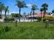 A gorgeous view of the community pool features a red roofed clubhouse and several tall palm trees at 402 Bouchelle Dr # 205, New Smyrna Beach, FL 32169