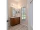 Neutral bathroom features a wood vanity, mirror and window with blinds at 404 Central Mariners Dr, Edgewater, FL 32141