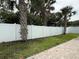 A pristine white vinyl fence encloses the backyard, enhancing privacy and security with lush palm trees scattered within the yard at 415 Jessamine Ave, New Smyrna Beach, FL 32169