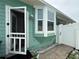 Home exterior with a screen door leading to a fenced area and a bay window at 415 Jessamine Ave, New Smyrna Beach, FL 32169
