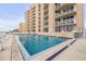 Exterior view of a pristine pool with crystal-clear water, surrounded by a tan building with white balconies at 421 S Atlantic Ave # 507, New Smyrna Beach, FL 32169
