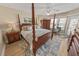Serene main bedroom featuring a four-poster bed, fan, and a view of the outside at 4670 Links Village Dr # D206, Ponce Inlet, FL 32127