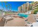 Exterior view of the community pool with lounge chairs, palm trees, and a glimpse of the building at 4670 Links Village Dr # D206, Ponce Inlet, FL 32127