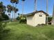 View of storage shed in a well-maintained backyard with lush green grass and tropical landscaping at 5018 Riverside Dr, Port Orange, FL 32127