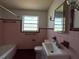 Retro pink bathroom with original tiles, a clean white sink, and a vintage-style mirror at 5018 Riverside Dr, Port Orange, FL 32127